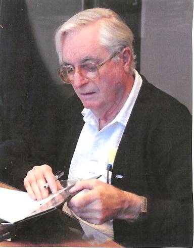 An older white man with combed-over white hair and glasses.